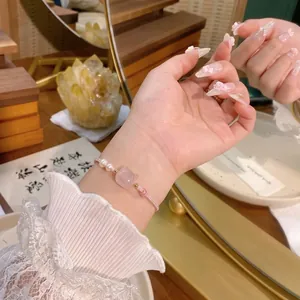 Nahaufnahme eines handgefertigten rosa Quarz-Armbands mit Perlen und Katzenstein am Handgelenk