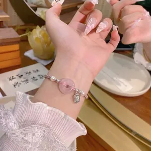 Detailansicht eines handgewebten Armbands mit rosa Kristall und Perlen am Handgelenk