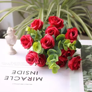 Detail shot of a vibrant red artificial rose bouquet with lush green eucalyptus leaves.