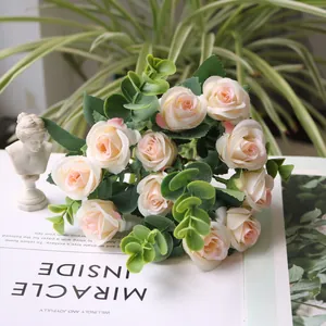Macro view of artificial cream roses bouquet with green eucalyptus leaves on a book
