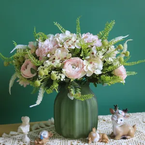 Elegante arreglo floral artificial con ranúnculos rosas en jarrón de vidrio verde