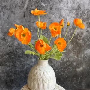 Detalle de flores de amapola de Islandia artificiales naranjas en un jarrón de cerámica