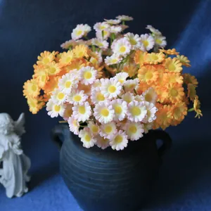 Detail shot of orange and pink artificial daisy bouquet in a vintage dark ceramic vase