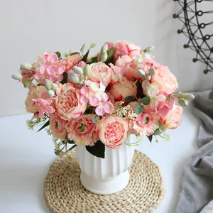 Detalle de un ramo de peonías y hortensias artificiales en un jarrón blanco moderno.