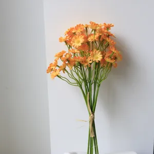 Detailed view of orange artificial daisy bouquet tied with natural straw string.