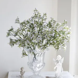 Detalle elegante de flores de gipsofila artificiales moradas en un jarrón de cristal.
