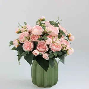 Elegant boeket roze kunstpioenen in een groene geribbelde glazen vaas voor decor