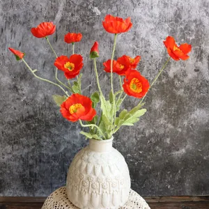 Amapolas de Islandia artificiales rojas en un jarrón de cerámica blanca con textura