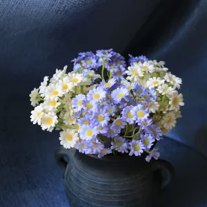Detail shot of lifelike artificial white and purple daisies in a dark ceramic vase