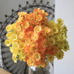 Close-up of vibrant yellow and orange artificial daisy flowers in a vase