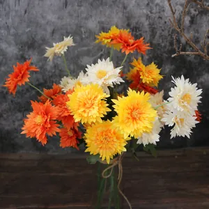 Vibrant orange and yellow artificial chrysanthemum bouquet in a twine-wrapped glass vase.