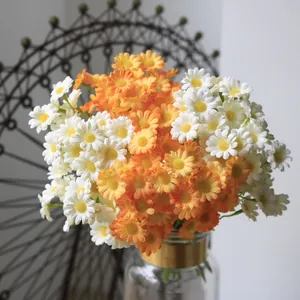 Close-up of artificial white and orange daisies in a glass vase for home decor