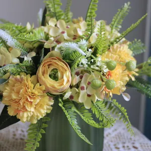 Primer plano de un ramo de flores artificiales amarillas con ranúnculos y claveles.