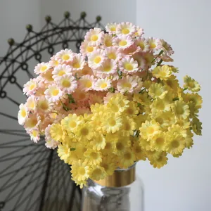 Detailed view of artificial pink and yellow daisies in a glass vase for home decor