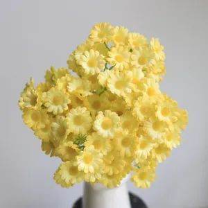Detailed view of vibrant yellow artificial daisy bouquet in a white minimalist vase