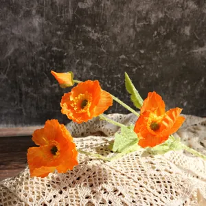 Vista de primer plano de amapolas artificiales naranjas sobre encaje de estilo vintage