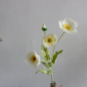 Primer plano de una flor de amapola blanca artificial con estambres amarillos.