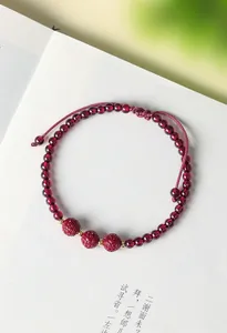 Dettaglio di un braccialetto di perle di granato con perle di cinnabro incise