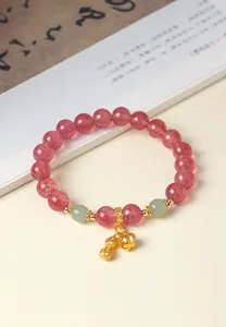 Detailansicht eines rosa Erdbeerquarz-Armbands mit einem goldenen Erdnuss-Anhänger