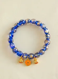 Nahaufnahme blauer Glasperlen mit Goldfolie und traditionellen goldenen Glücksbringern.