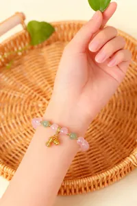 Detailansicht eines Armbands aus Rosenquarz mit Erdnuss-Anhänger am Handgelenk
