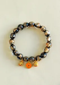 Detailansicht der goldgesprenkelten schwarzen Glasperlen und Glücksbringer am Armband