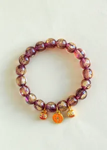 Detaillierte Ansicht eines lila Glasperlen-Armbands mit Goldfolie und Glücksbringern