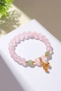 Makrodetail eines Rosenquarz-Armbands mit grüner Jade und goldenem Erdnuss-Anhänger