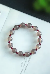 Detalle de pulsera de cuentas de ágata gris natural y granate para mujer