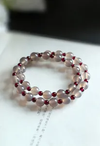 Primer plano de una elegante pulsera de doble capa de ágata gris natural y cuentas de granate