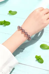 Primer plano de una pulsera de cuentas de ágata gris y granate natural en una muñeca.