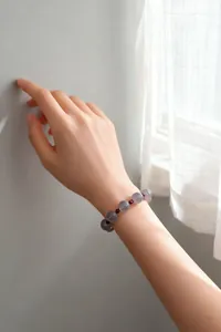 Elegante pulsera de cuentas de ágata gris natural y granate lucida en una muñeca femenina