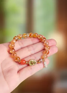 Detailansicht eines gelben Kristallarmbands mit Jade-Anhänger in Form eines Flaschenkürbisses