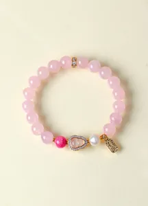 Detaillierte Makroansicht eines rosa Kristallperlenarmbands mit Perle und goldenem Anhänger
