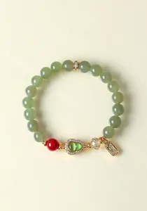 Detail eines Hetian-Jade-Perlenarmbands mit goldenem Feng-Shui-Anhänger und Glücksbringer.