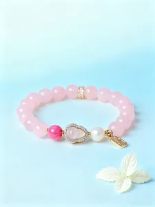 Detailansicht eines rosa Kristallarmbands mit einem Kürbis-Anhänger und einer eleganten Perle