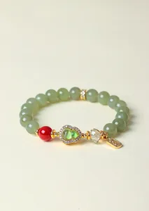 Detail eines Armbands aus Hetian-Jade mit Wu Lou-Anhänger und goldenen Akzenten.