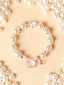 Dettaglio del braccialetto di perle bianche con ciondolo a fiore in cristallo rosa