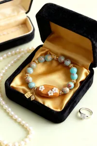 Détail rapproché du bracelet vintage en pierre naturelle avec breloque fleurie en bois noir