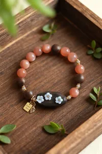 Détail du bracelet en perles de pierre de Shoushan et santal avec breloques de fleurs
