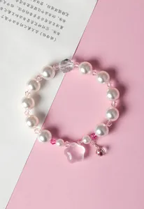 Dettaglio di elegante bracciale di perle bianche con cristalli rosa e ciondolo stella