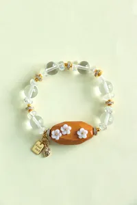 Gros plan d'un bracelet en perles de cristal avec perle en bois de santal et fleurs