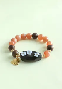 Détail d'un bracelet en perles avec pierre naturelle et breloque en bois de santal