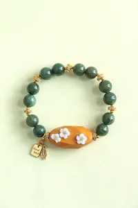Vue détaillée du bracelet en perles de pierre vert foncé avec perle en bois et fleurs sculptées