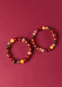 Détail du bracelet en agate rouge et œil de tigre avec de fins motifs dorés