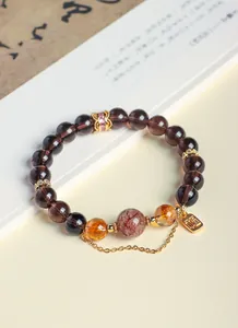 Detailed view of natural obsidian and citrine crystal bracelet with gold Fu charm tag