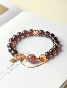 Detail view of a natural obsidian and super seven crystal beaded bracelet with a Fu charm.