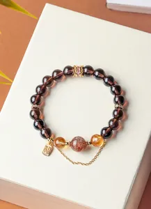 Detailed view of smoky quartz and strawberry quartz bracelet with gold luck charm