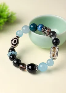 Macro view of Tibetan style bracelet featuring Dzi bead and Vajra pestle charm