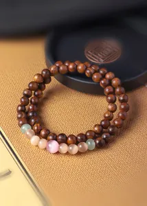 Close-up of double-layer sandalwood prayer beads with colorful cat's eye gemstones